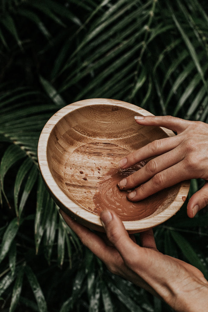 girls hands mixing clay in wooden bowl